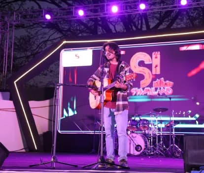 Student performing on stage with a guitar